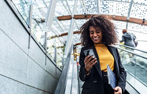 A woman uses her smartphone on an escalator